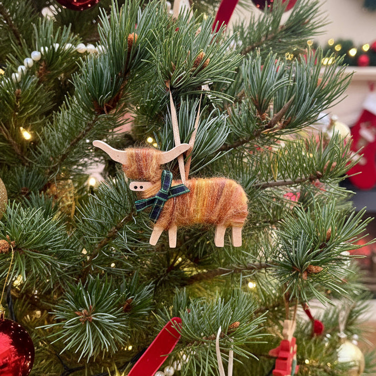 Knitted sheep ornament with a green bow tie hanging on a Christmas tree.